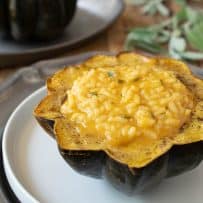A side view of pumpkin risotto stuffed acorn squash with another in the background