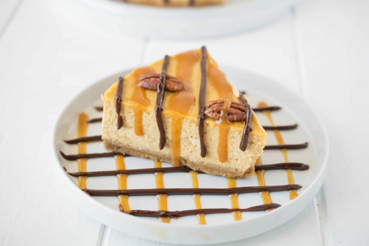 A white plate decorated with chocolate and caramel with a slice of pumpkin turtle cheesecake
