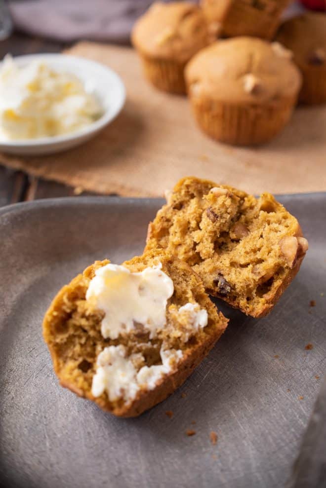 A pumpkin walnut muffin cut in half spread with butter
