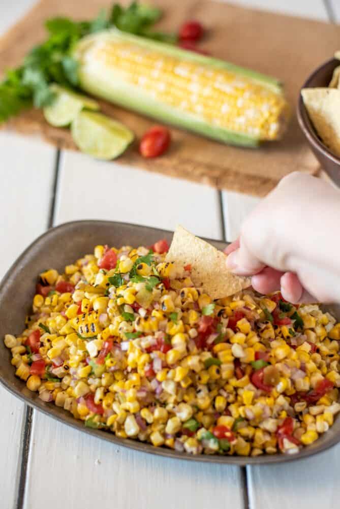 Using a tortilla chip to scoop up corn salsa