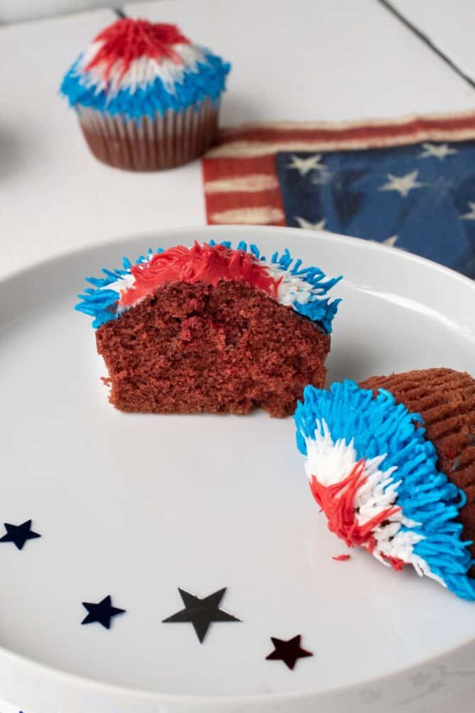A red velvet cupcake cut in half on a white plate