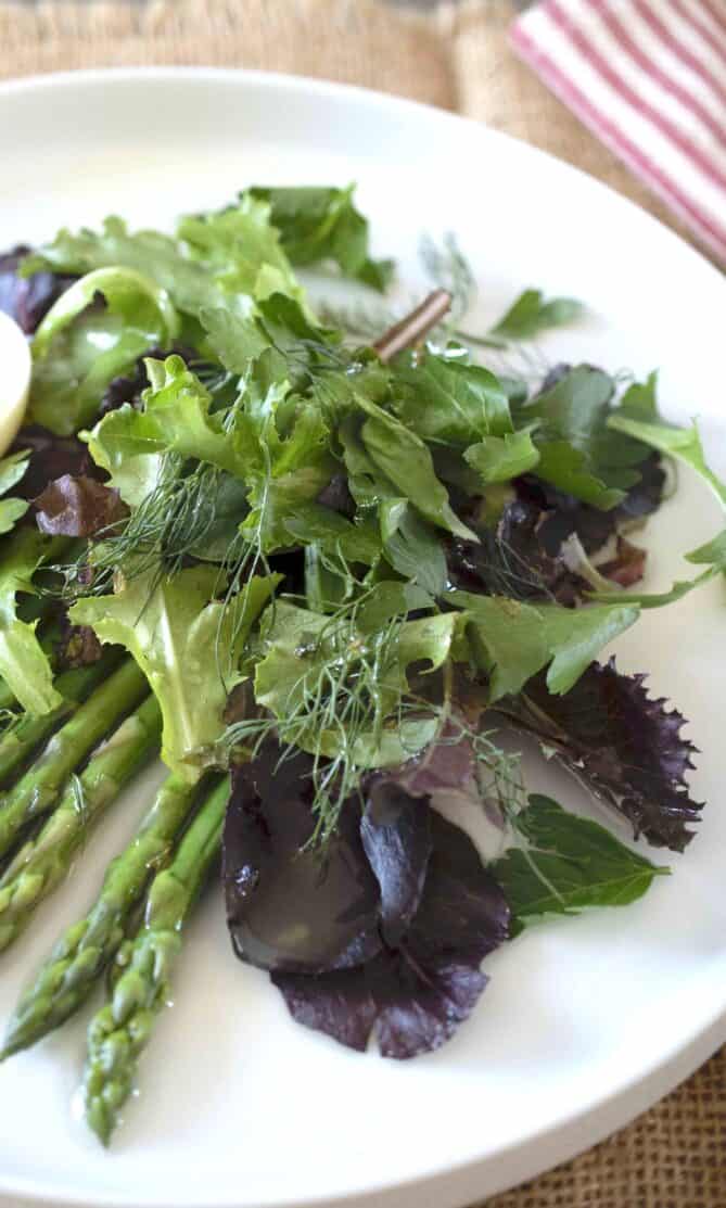 Salad greens piled on a white plate