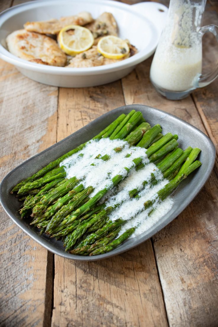Asparagus served on a pewter plate with lemon ricotta sauce