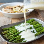 Pouring lemon ricotta sauce over roasted asparagus