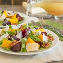 Pouring dressing onto a beet and arugula salad