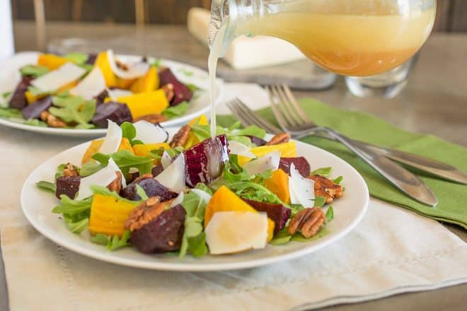 Pouring dressing onto a beet and arugula salad