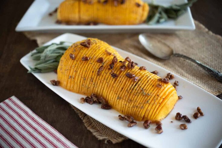 A half of a butternut squash, sliced and topped with pecans