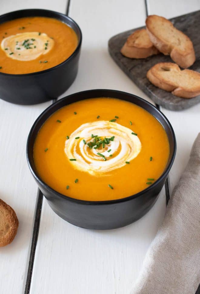 A bowl of Roasted Carrot Ginger Soup garnished with sour cream and chives
