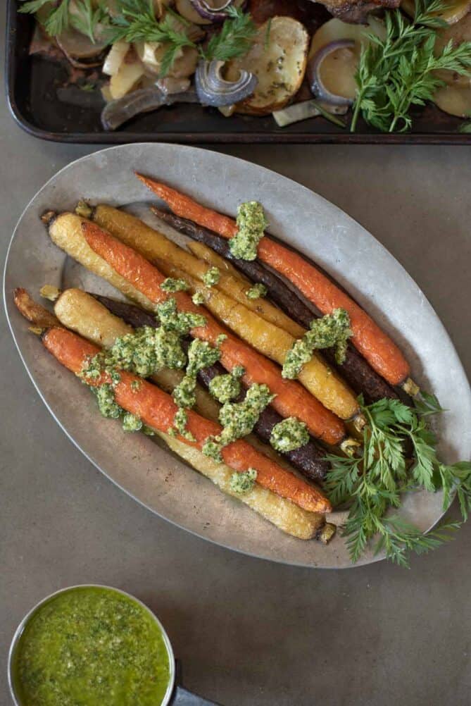 Colored carrots on an oval plate served with pesto sauce