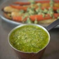 A small copper pan filled with vibrant green spring garlic pesto