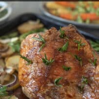 Roast lamb with a crispy crust with fresh rosemary on top of sliced and roasted potatoes