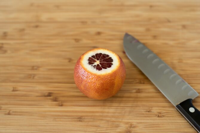 A blood orange with the top cut off and a knife