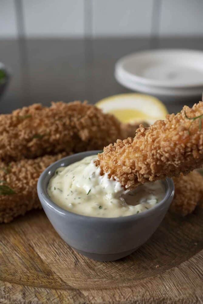 Dipping a crispy fish finger/fish stick into tartar sauce