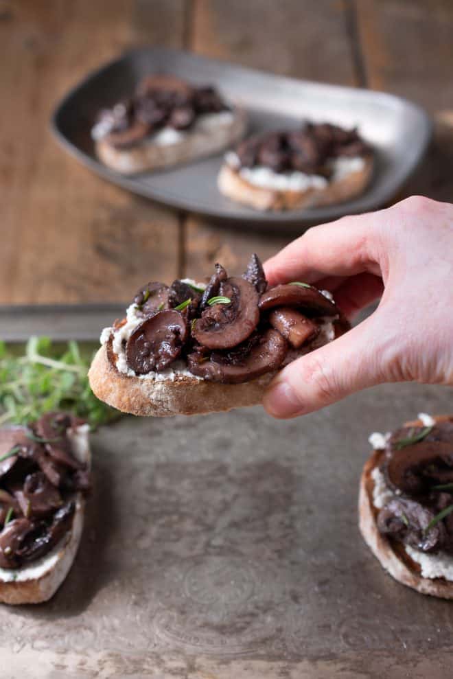Holding a sautéed mushroom and rosemary bruschetta