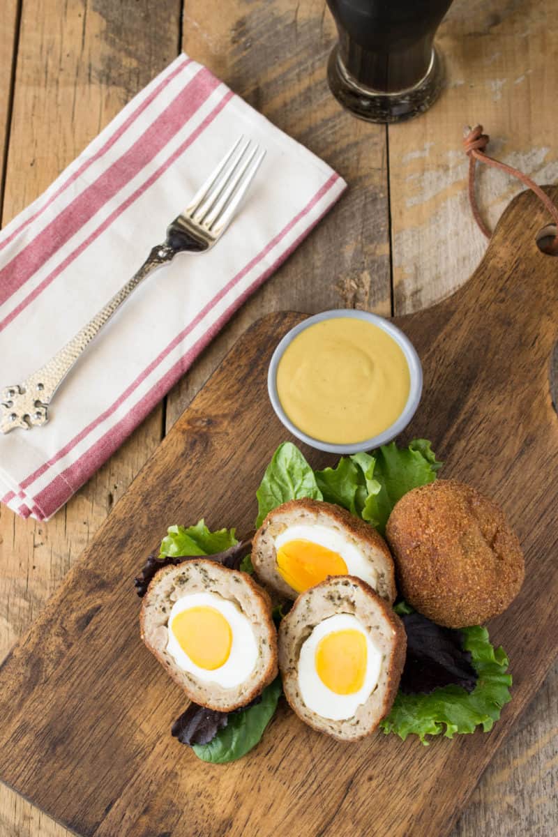 Scotch eggs from above on a board with mustard sauce