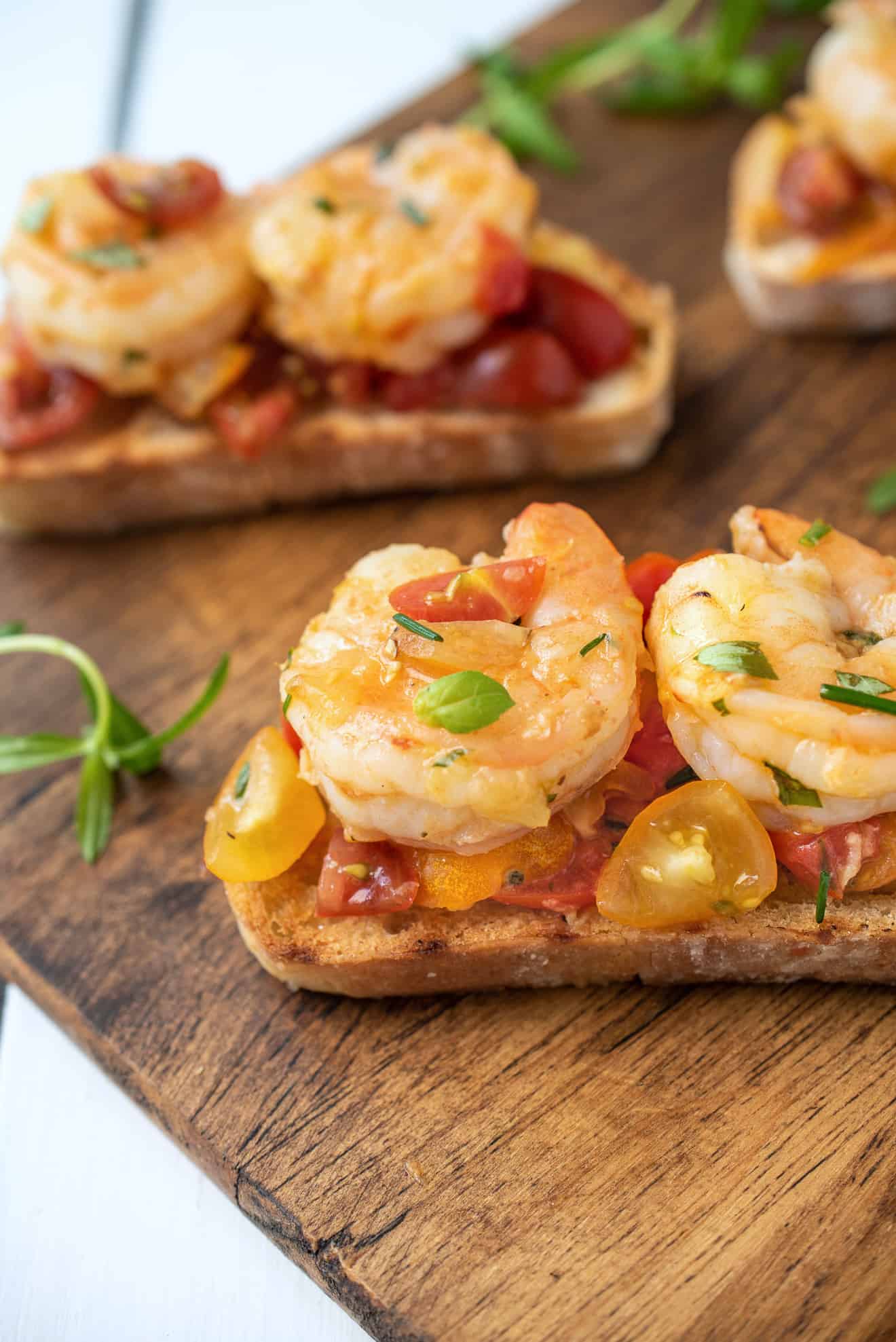 Grilled bread slices topped with shrimp and cherry tomatoes