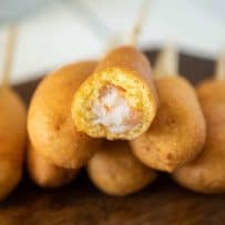 A cut open shrimp corn dog showing the shrimp inside