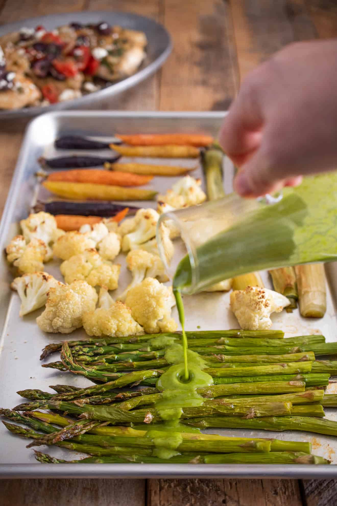 Pouring herb sauce over roasted asparagus