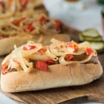 Onions and peppers piled on top of a bratwurst sandwich
