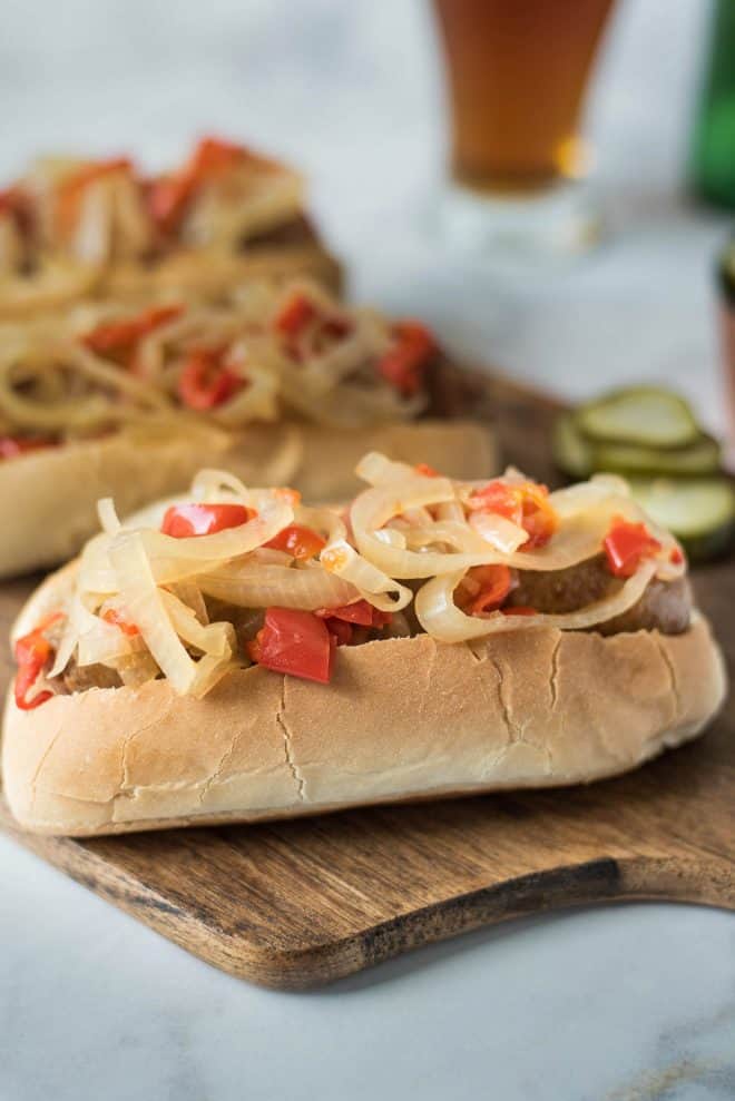 Onions and peppers piled on top of a bratwurst sandwich
