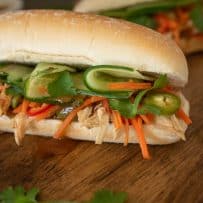 A closeup showing the banh mi filling of shredded chicken, shaved cucumber, carrot slaw and cilantro