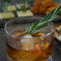 A short rocks glass with a smoked Christmas Manhattan cocktail