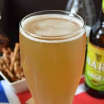 Hard cider and lager in a glass with a foamy head