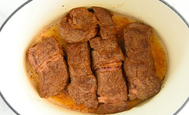 Spice rubbed chuck roast browning in a pan