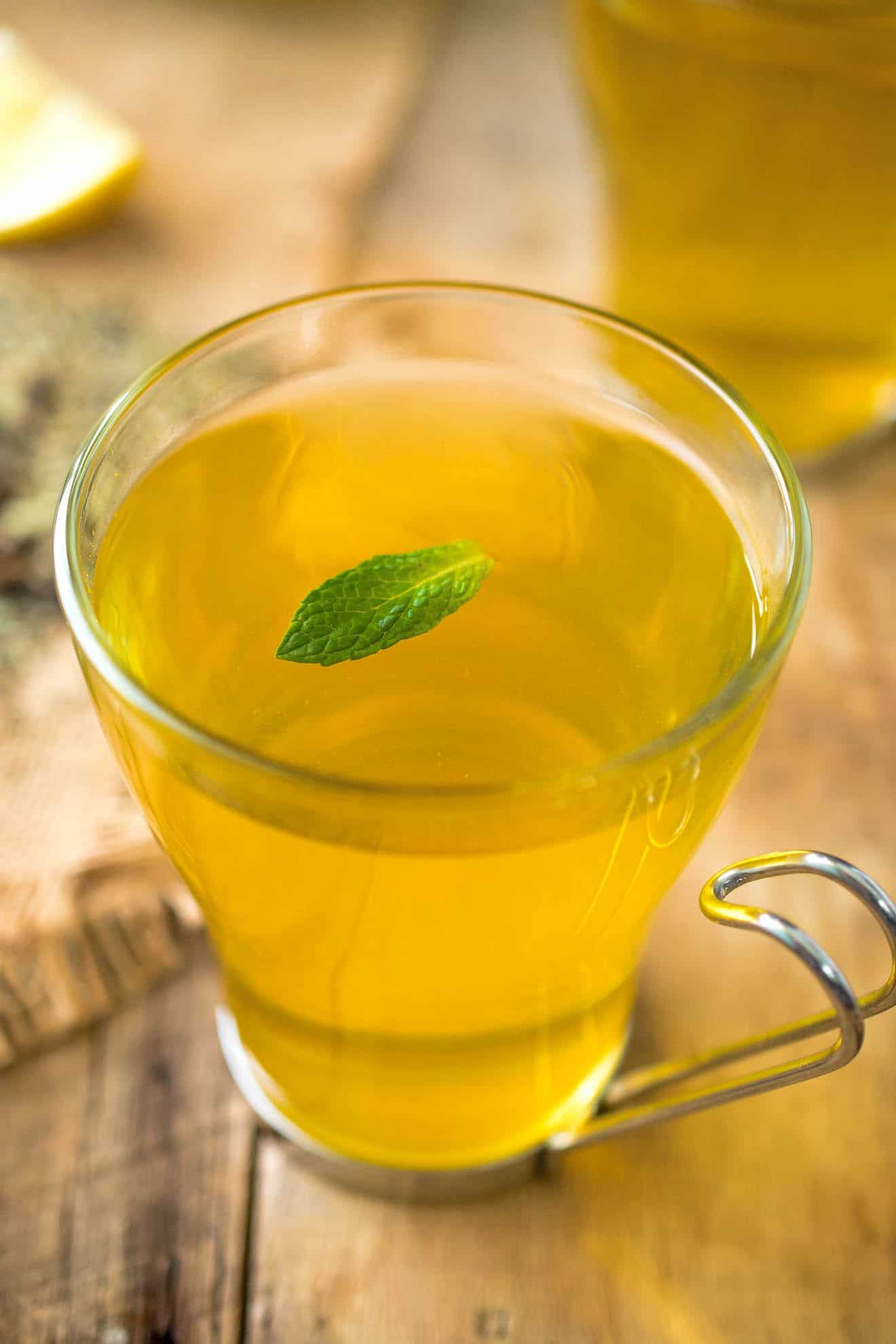 A glass mug of herbal tea with a mint leaf garnish
