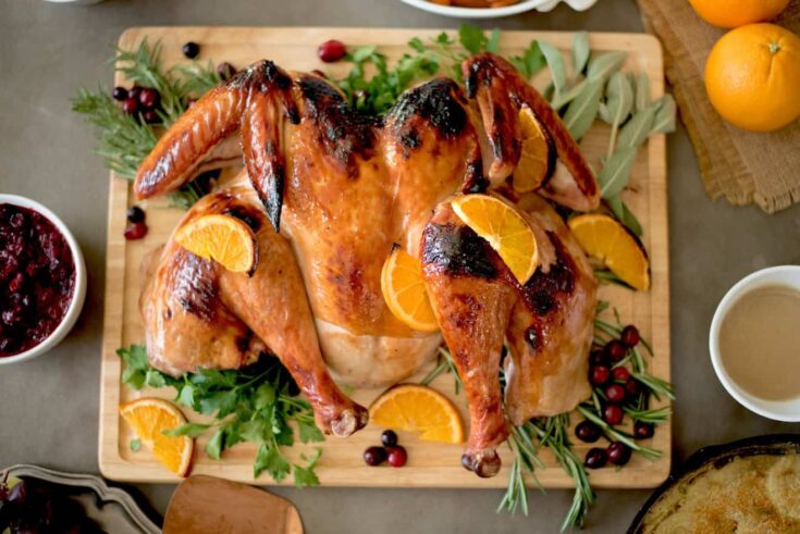 A spatchcock roasted turkey garnished with herbs and orange slices.