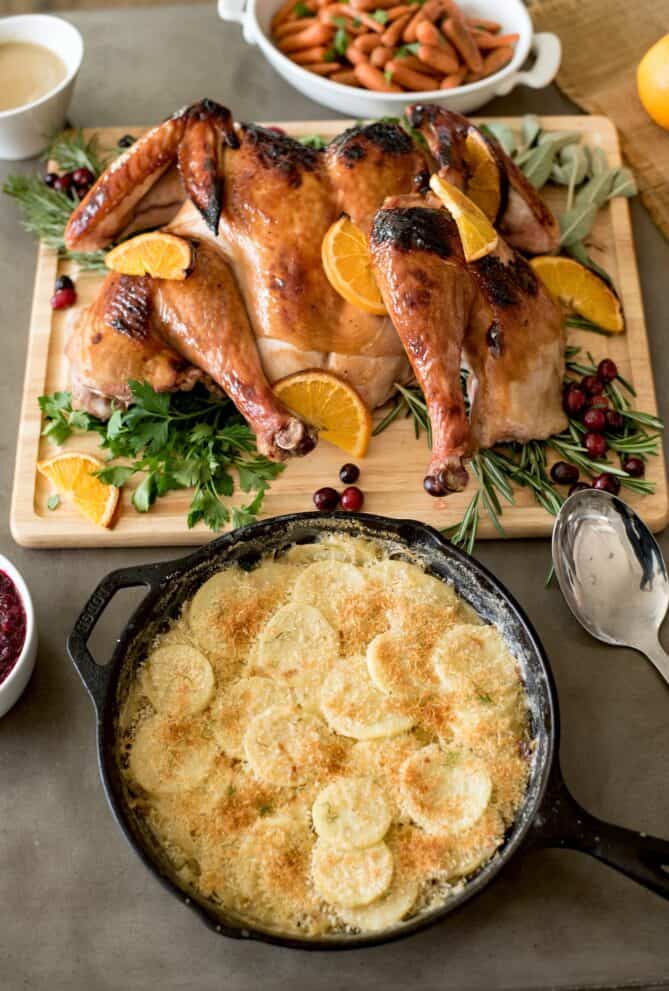 A whole roasted turkey served with potato gratin in a cast iron pan