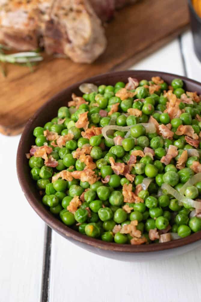 A closeup of fresh peas with crispy pancetta bits