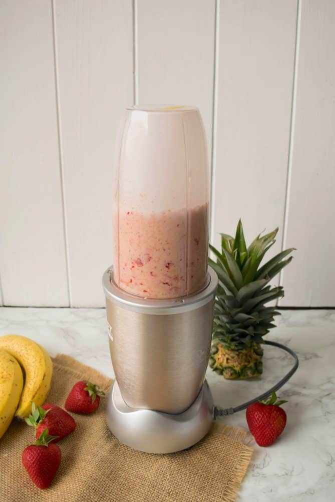 Blending a smoothie in a Nutribullet blender surrounded by fruit
