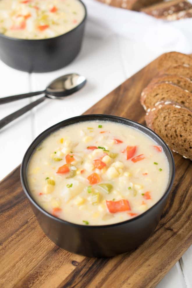 Summer corn chowder served in a black bowl with bread