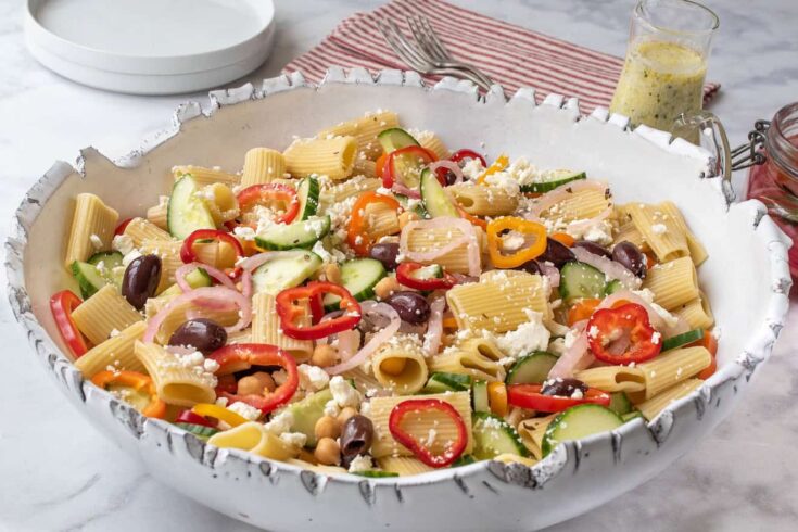 A bowl of pasta salad with vegetables and cheese.