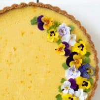 Summer mango pie with half of the top decorated with viola edible flowers