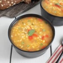 Corn soup served in black bowls with a loaf of bread