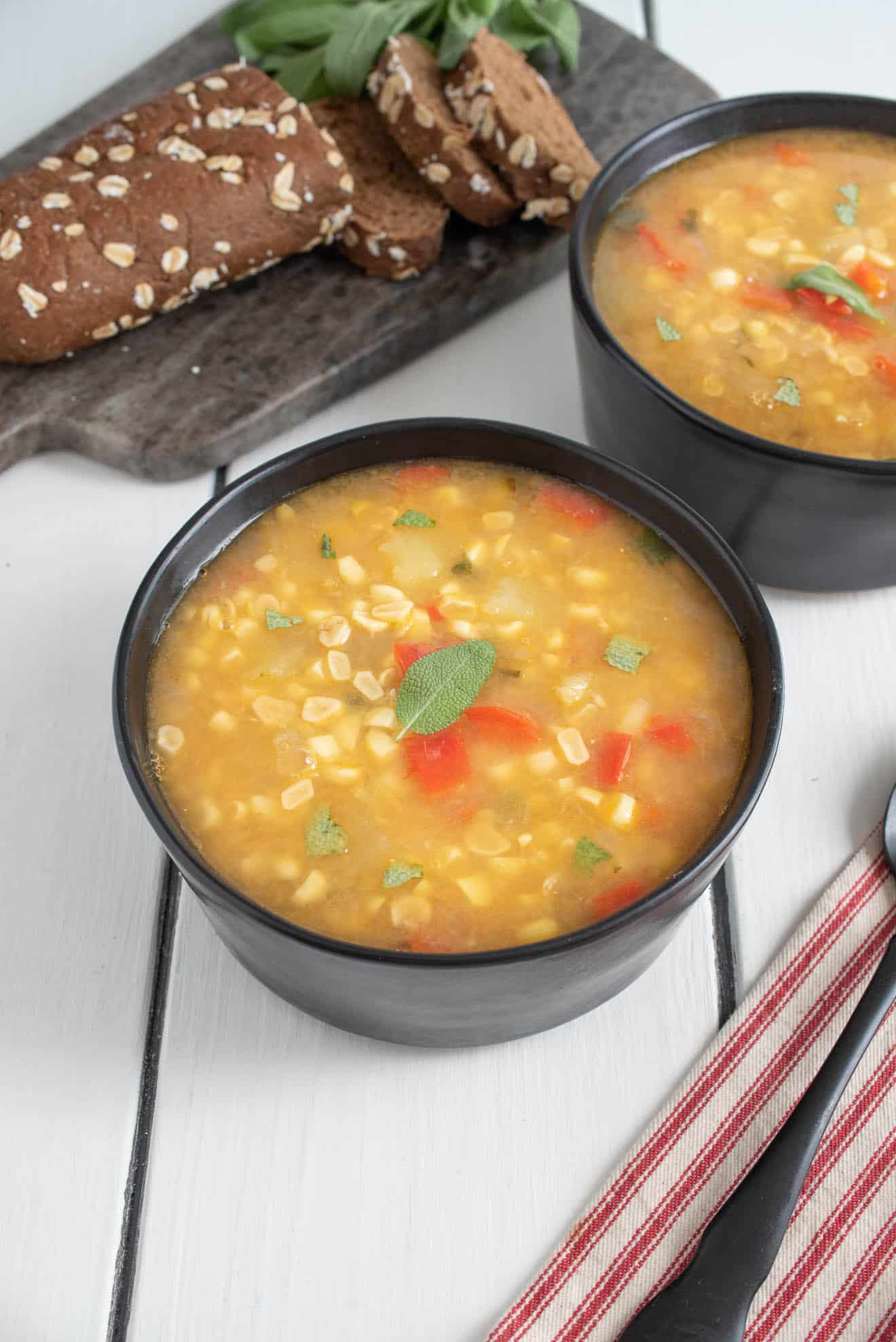 Corn soup served in black bowls with a loaf of bread