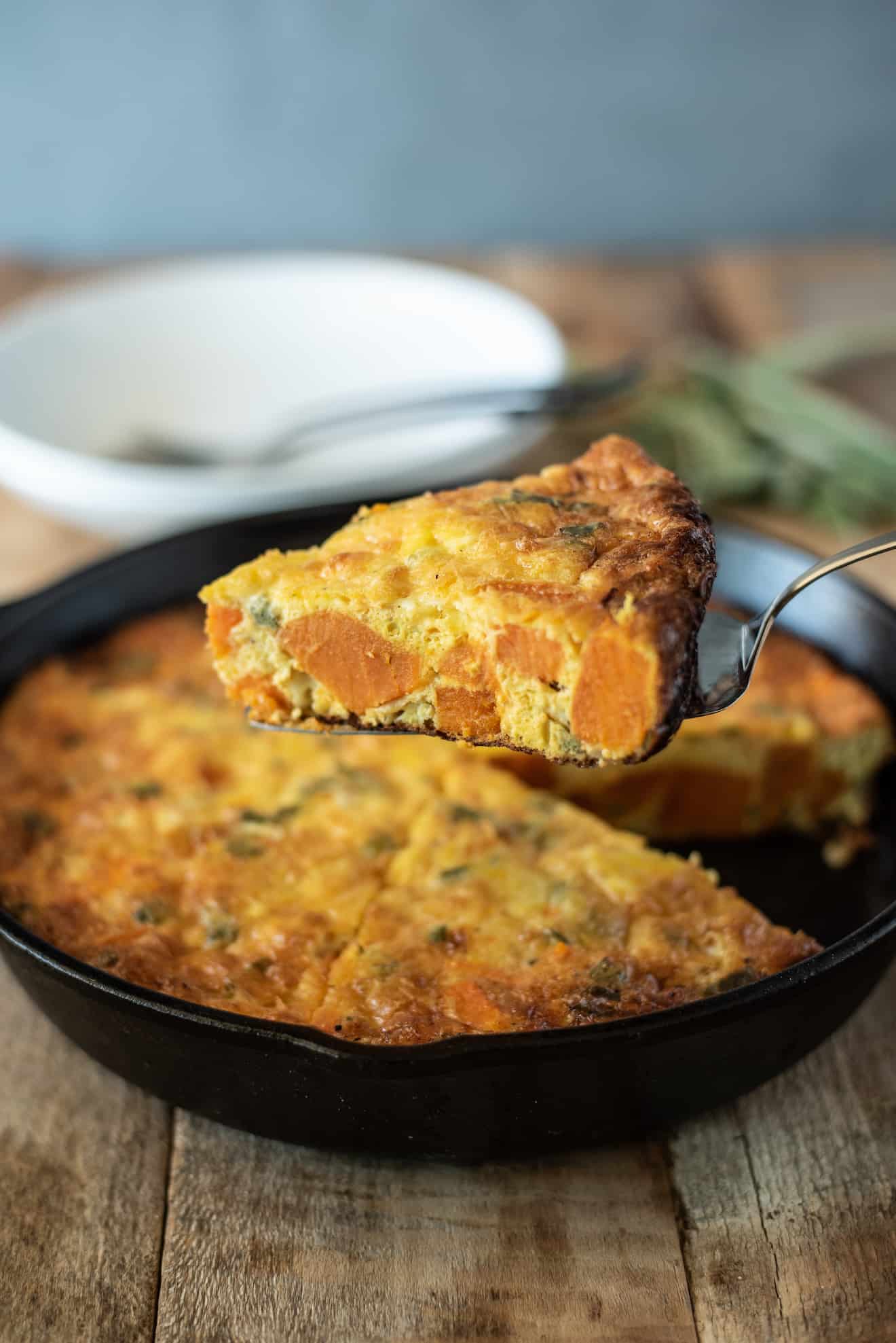 A slice of sweet potato and sage frittata showing the orange sweet potato inside