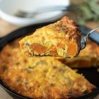 Serving a slice of sweet potato and sage frittata with chunks of sweet potato and sage showed inside