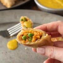 A samosa cut open showing sweet potato and pea filling inside