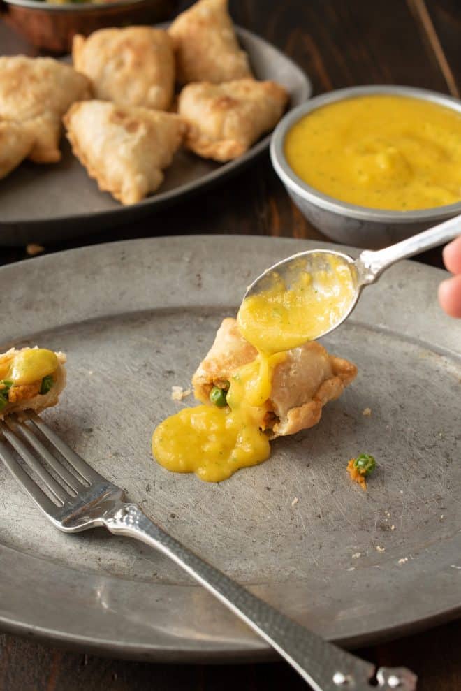 Drizzling mango puree onto a sweet potato samosa