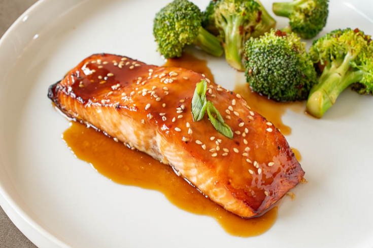 Teriyaki Glazed Salmon on a white plate with green onion and broccoli
