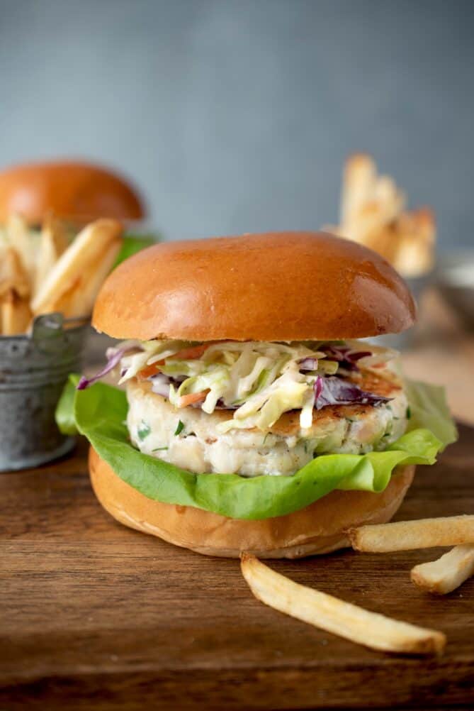 A side view of a fish burger topped with coleslaw on a bun