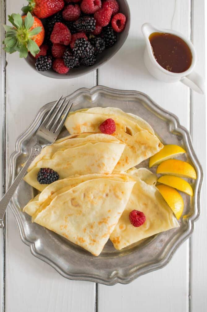 Pancakes on a pewter plate from overhead with raspberries and blackberries