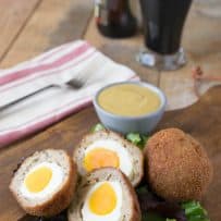 Scotch eggs cut in half showing the yellow yolk and sausage inside