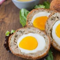 Scotch eggs cut in half on a board
