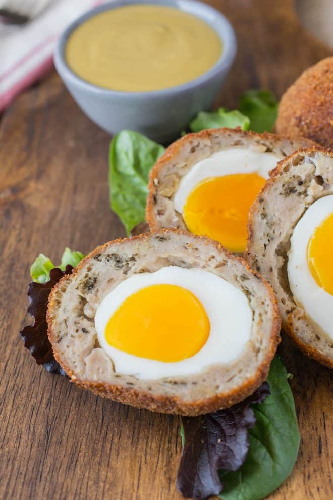 Scotch eggs cut in half on a board