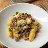 Bolognese sauce mixed with gnocchi in a white bowl