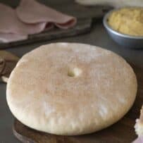 A round loaf of bread called stottie on a board.